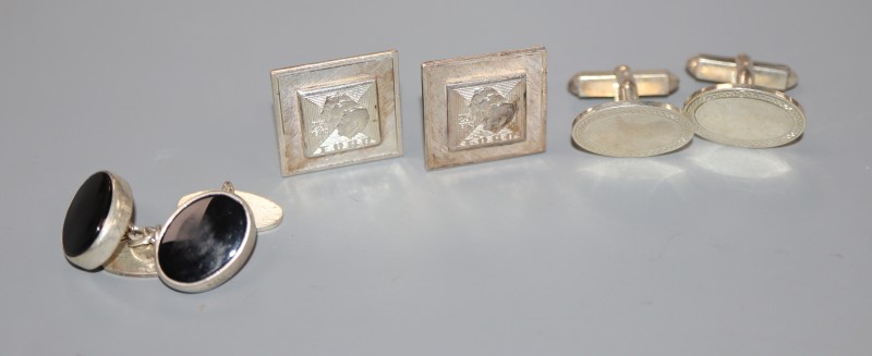 A pair of silver cufflinks and two other pairs of cufflinks.